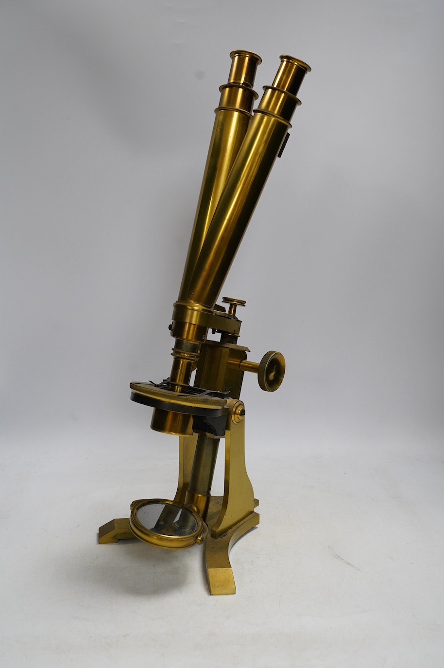 A 19th century brass compound binocular microscope, engraved to the base Baker, 244 High Holborn, London, with four brass cased objective lenses, 47cm high. Condition - fair to good